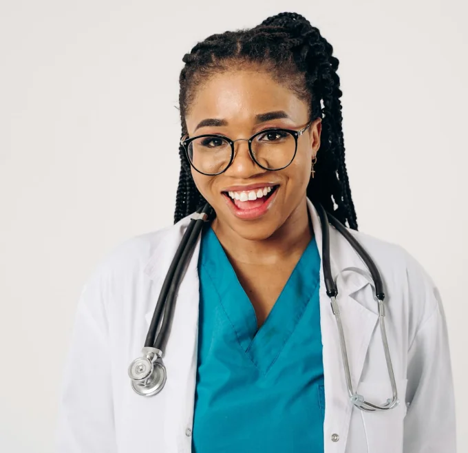 A nurse with a stethescope round her neck, smiling at the camera