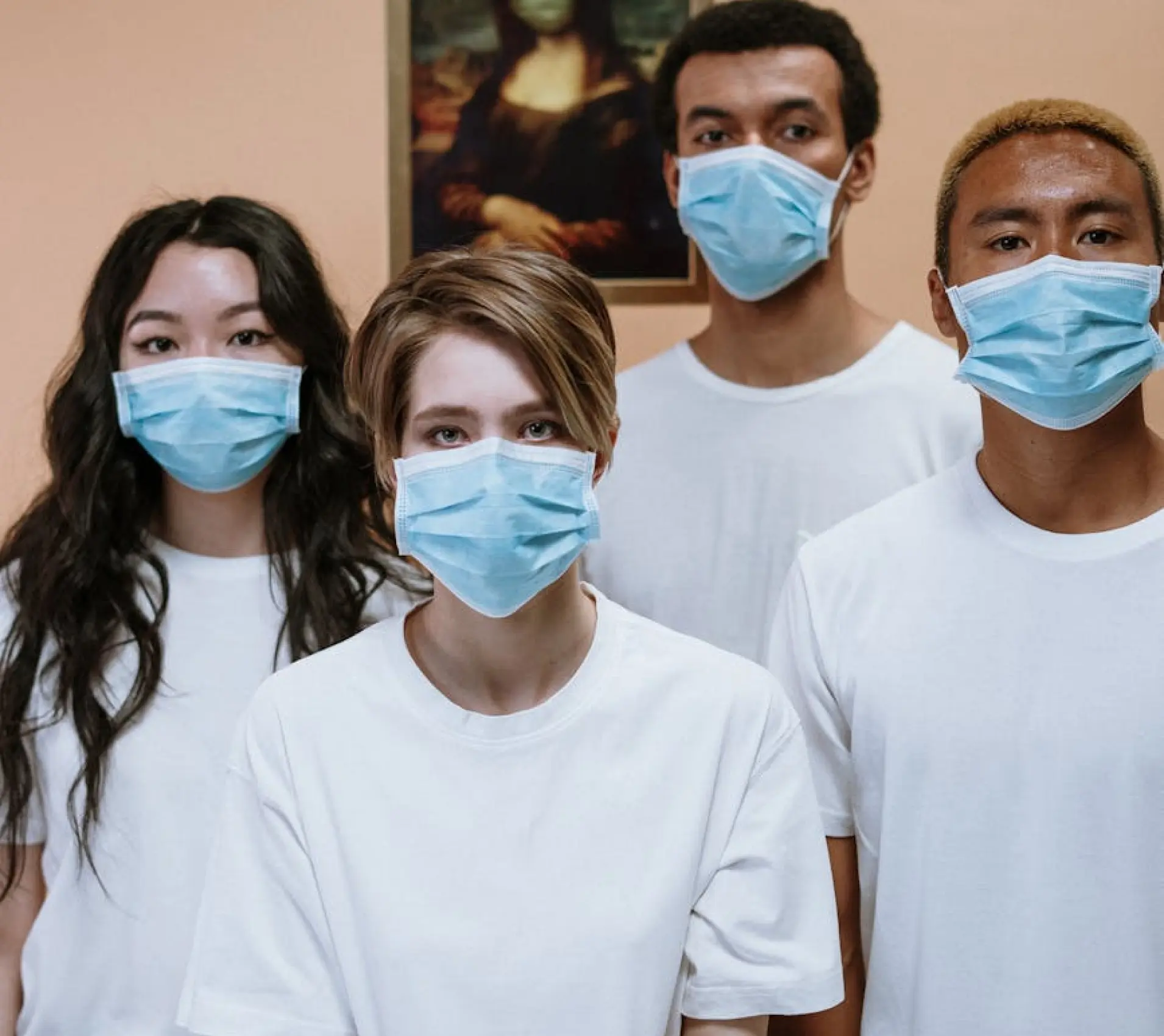 A group of four nurses two females, two males, with nose masks on and looking into the camera